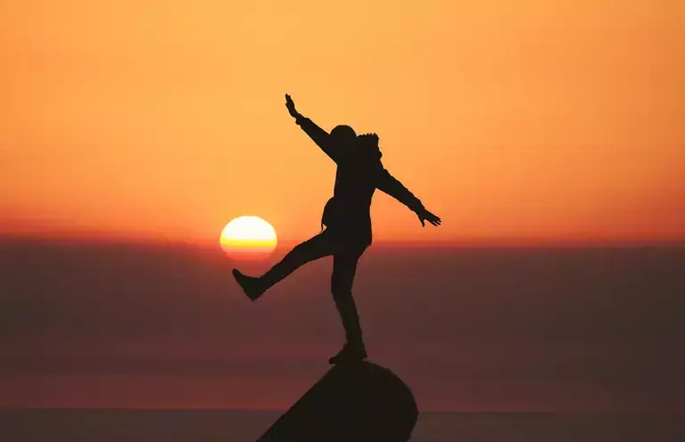 Person standing on a rock during sundown