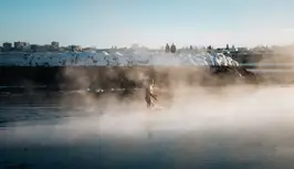 A man is seen walking into the ocean amid rising steam.